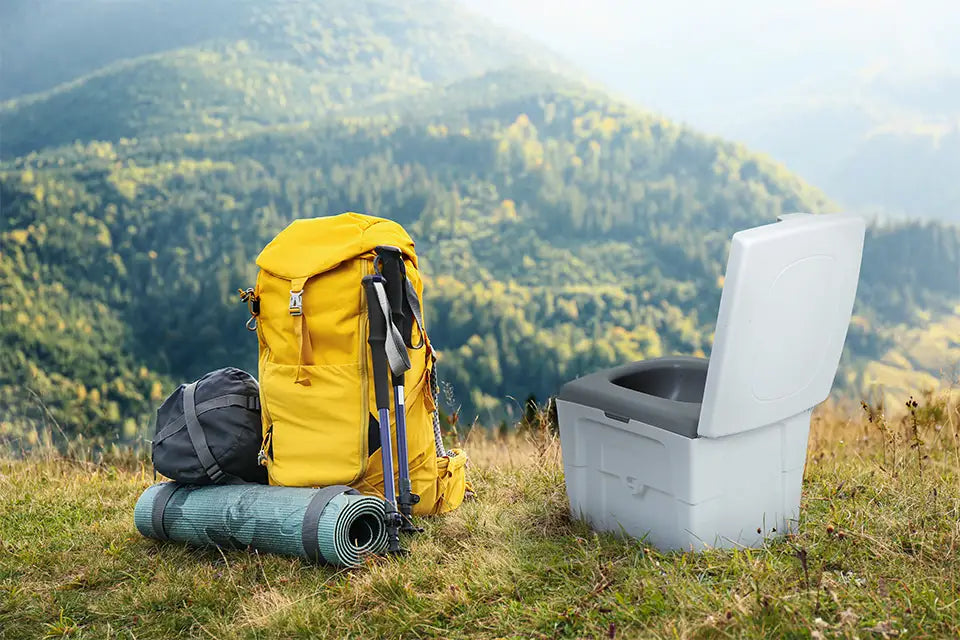 The WandaGO Lite composting toilet stands next to a backpacker overlooking the mountains.
