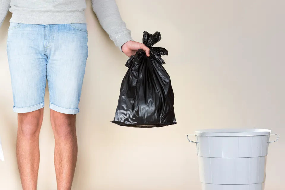 Man holding bag next to portable camping toilet
